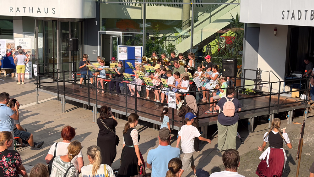 Die Bläserklasse der 3. Klassen auf der Bühne vor dem neuen Rathaus